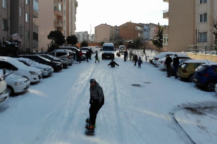 Pendik’te kayaksever bahçede snowboard yaptı, çocuklar poşetle eşlik etti